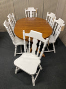 Oval wood dining table with six white spindle back chairs. 44515