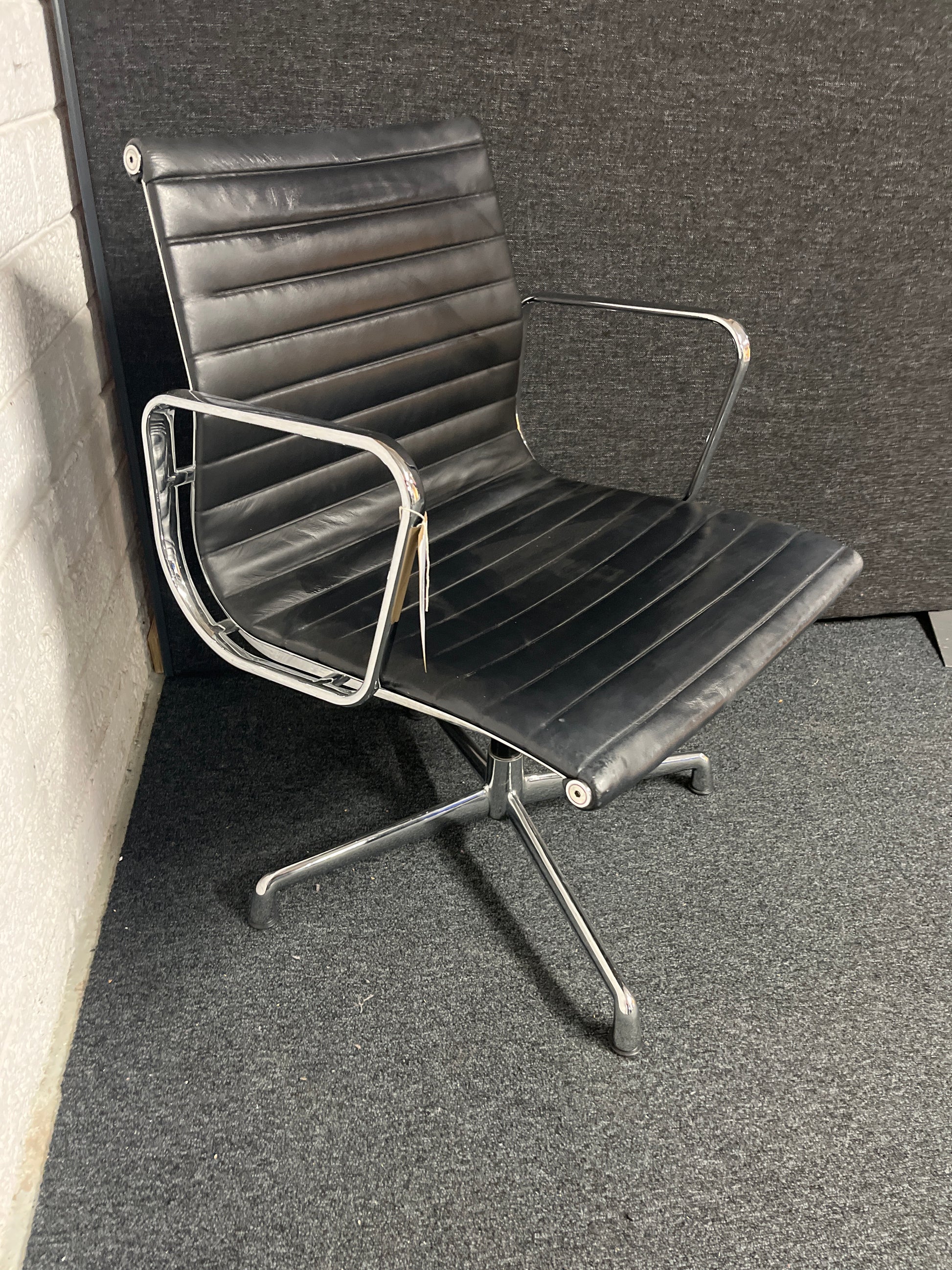 Eames style black leather low back swivel chair with polished chrome base on pads or castors