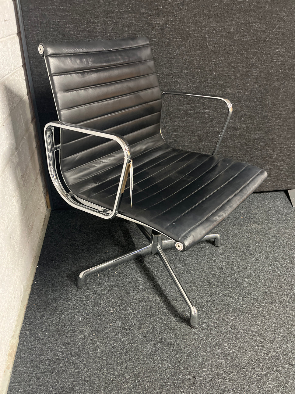 Eames style black leather low back swivel chair with polished chrome base on pads or castors