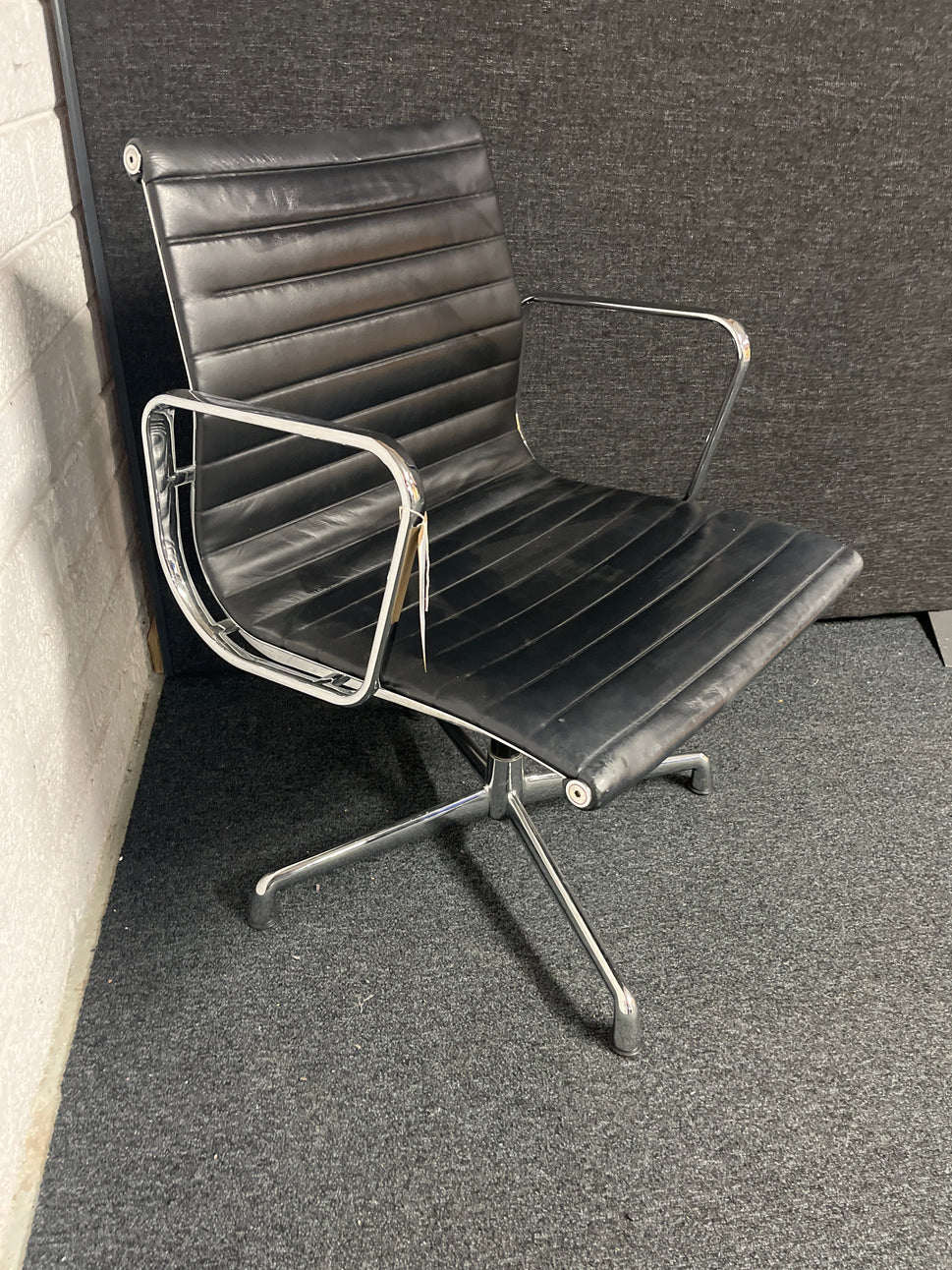 Eames style black leather low back swivel chair with polished chrome base on pads or castors