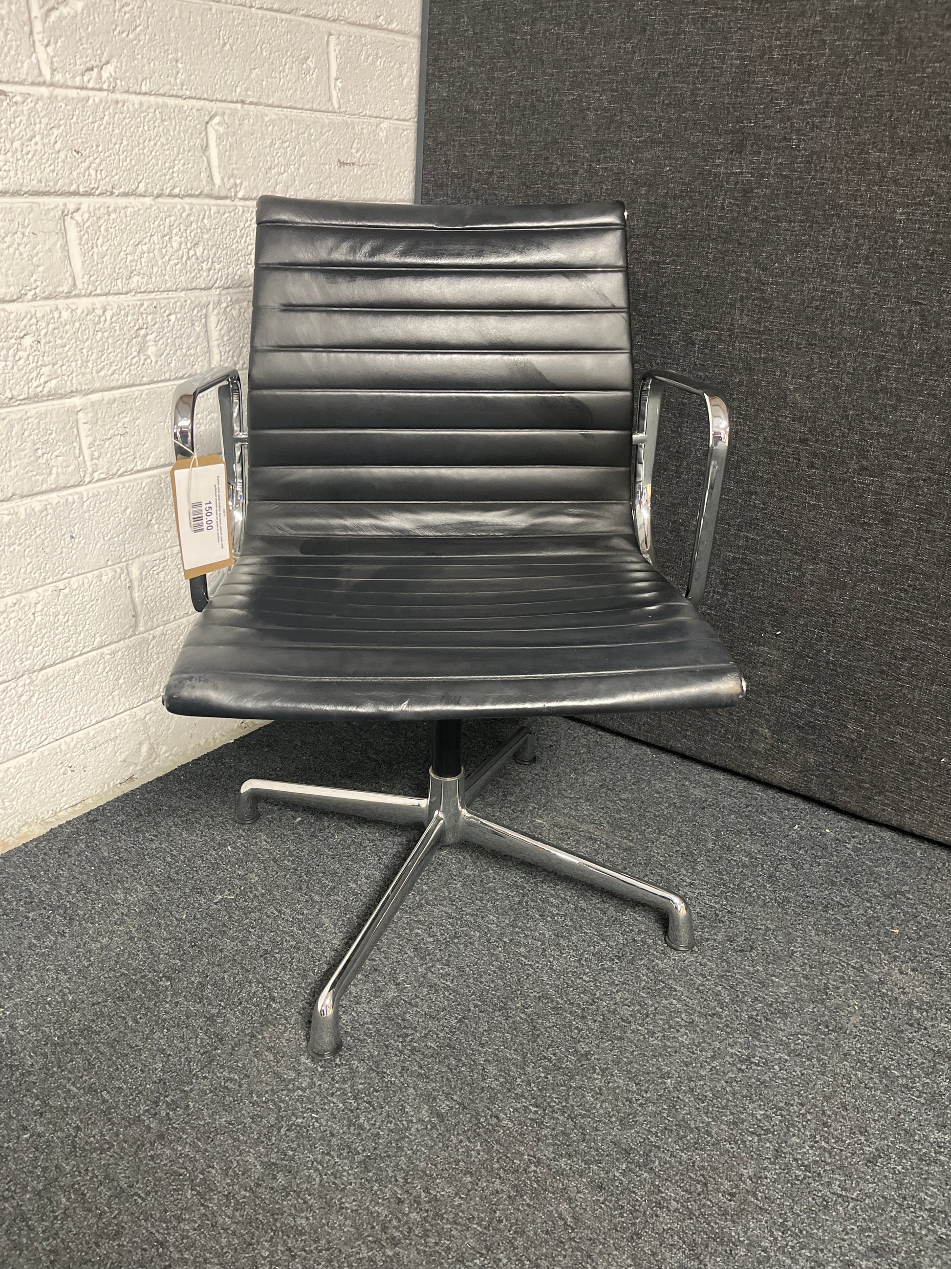 Eames style black leather low back swivel chair with polished chrome base on pads or castors