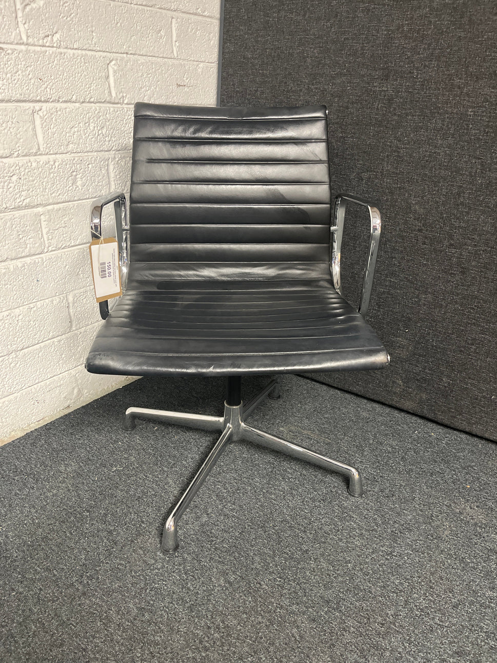 Eames style black leather low back swivel chair with polished chrome base on pads or castors