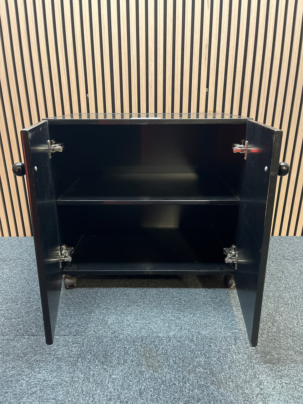 Low black laminate two door storage unit on castors (H 66 x W 70 x D 50 cm)