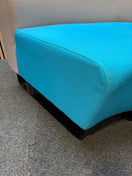 Two-piece curved fabric seating modules in grey and teal blue.