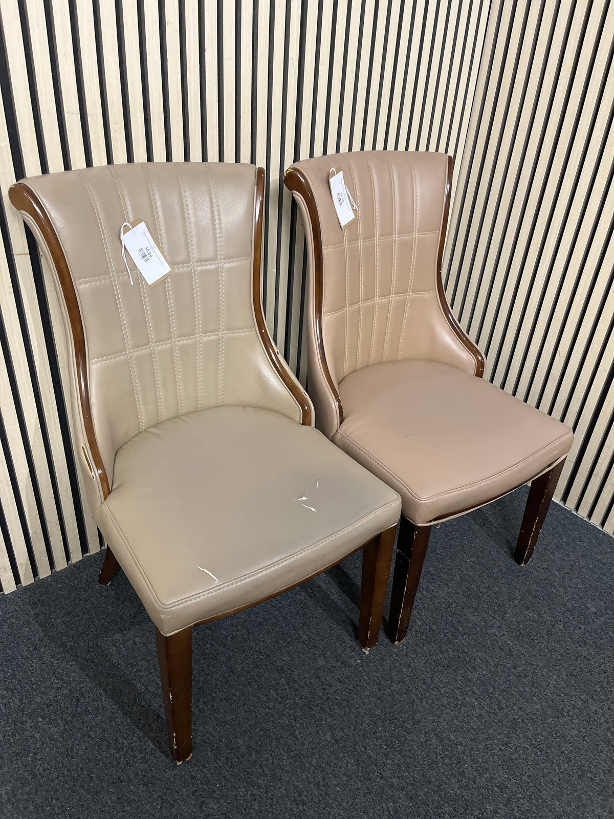 Two grey stitched faux leather dining chairs with wooden trim. 44373