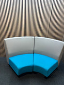 Two-piece curved fabric seating modules in grey and teal blue.