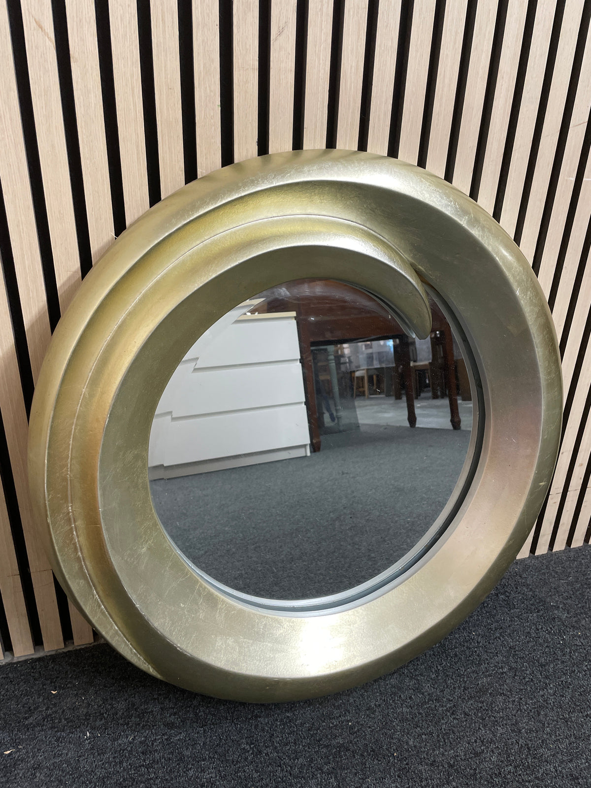 Circular wall mirror featuring a thick gold swirl-effect frame. 44410