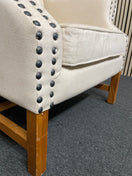 Beige tufted wingback armchair with decorative black nailhead trim detail. 44518
