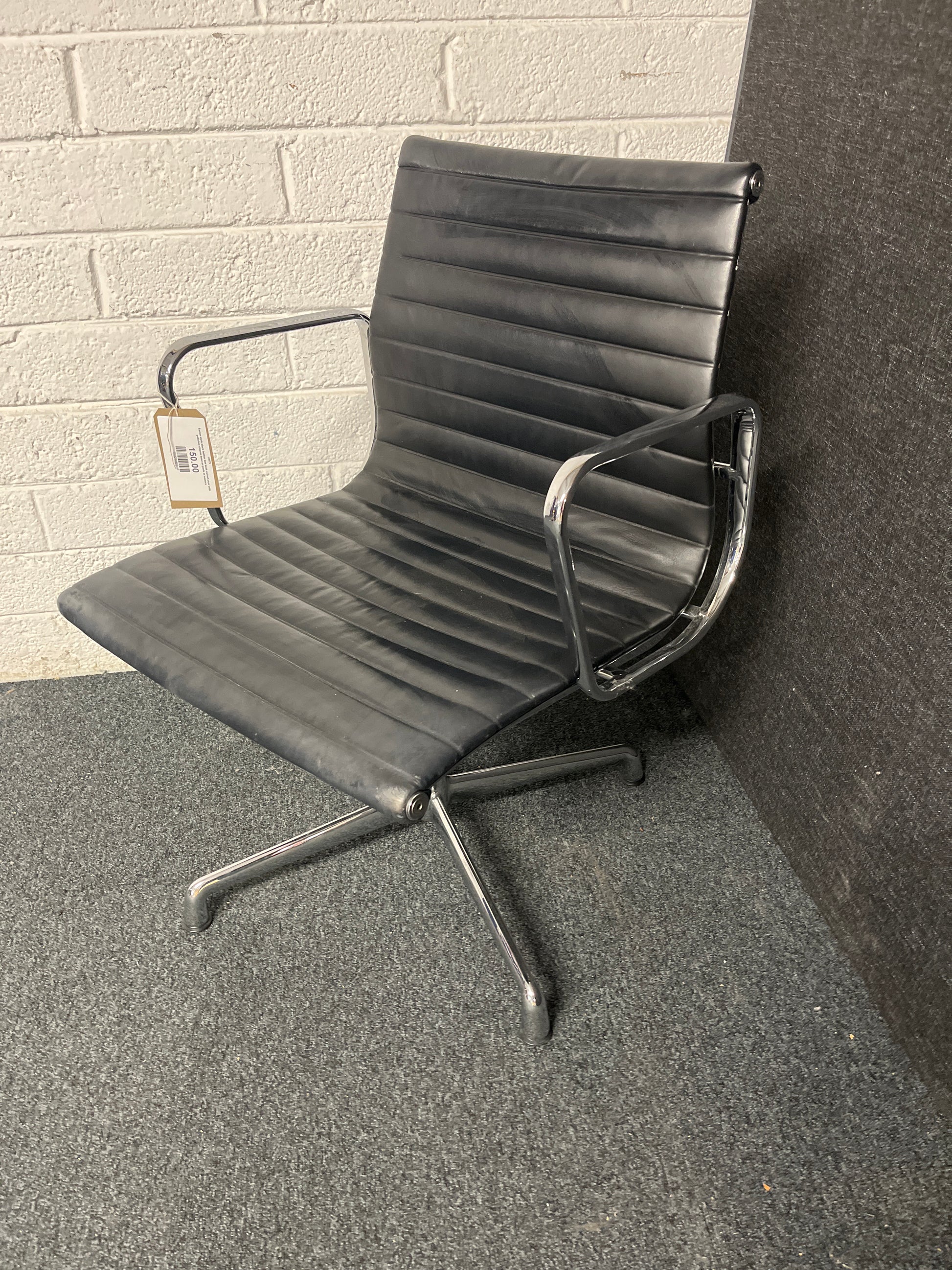 Eames style black leather low back swivel chair with polished chrome base on pads or castors