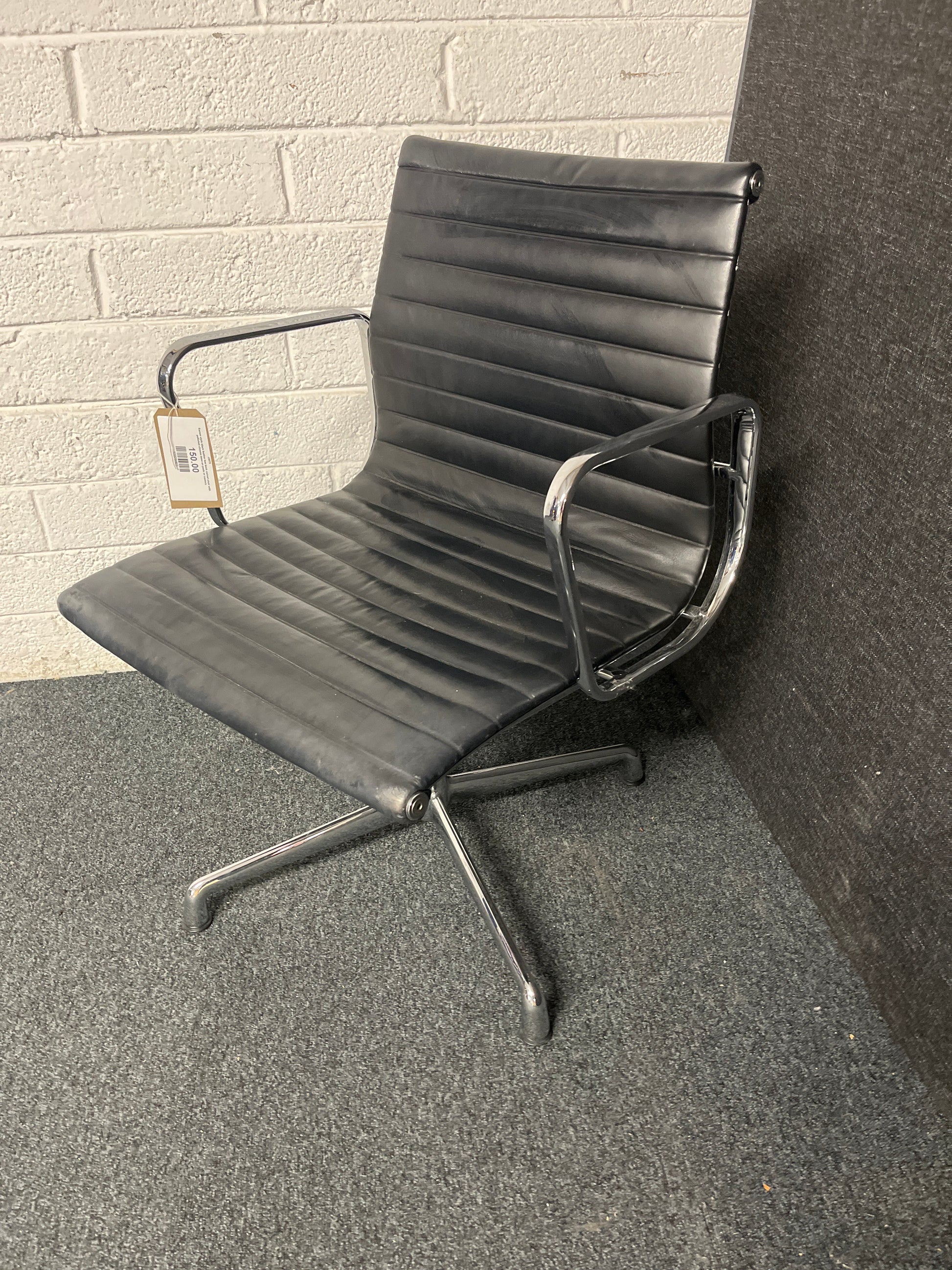Eames style black leather low back swivel chair with polished chrome base on pads or castors