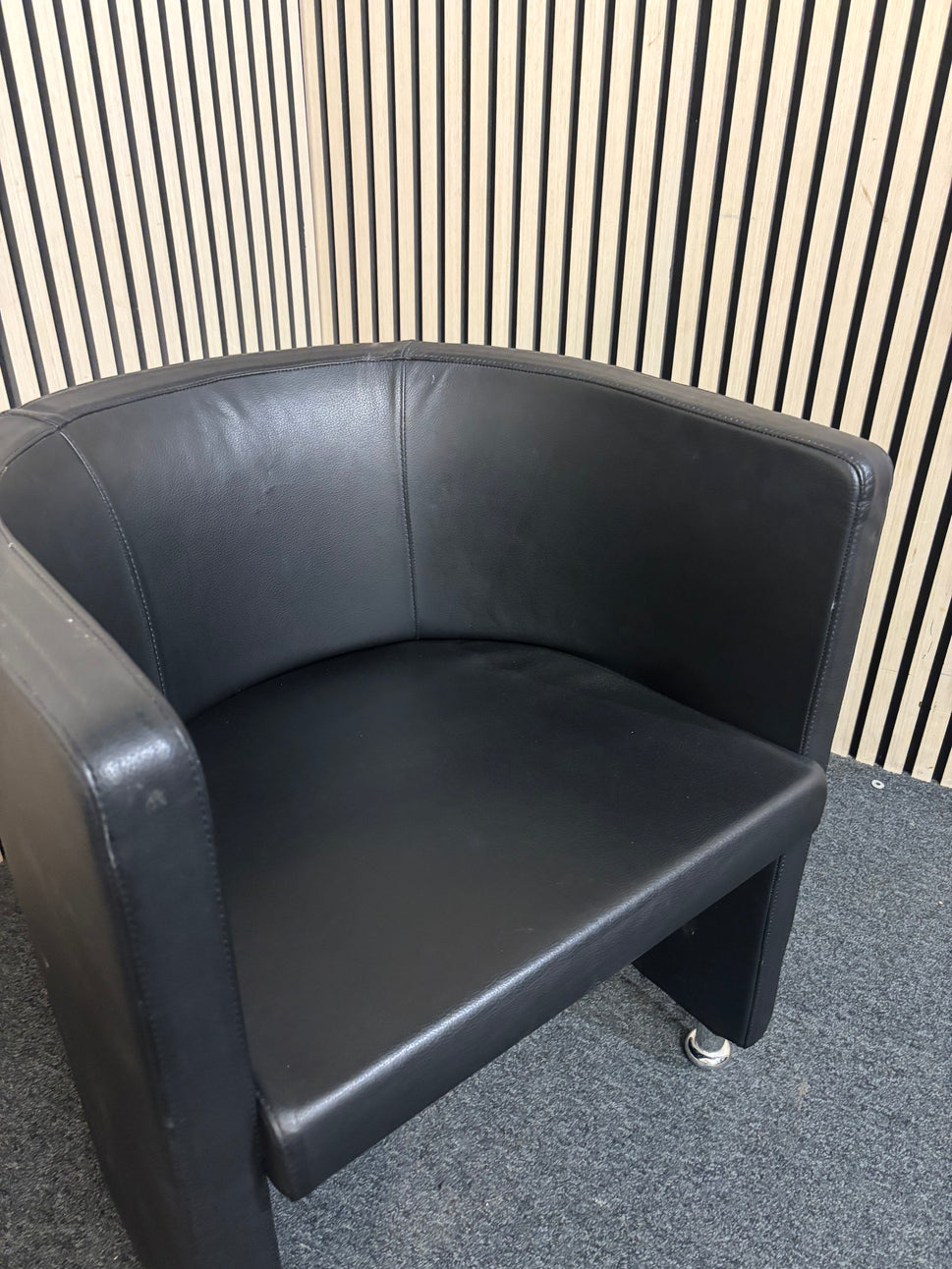 Dark leather curved back tub chair