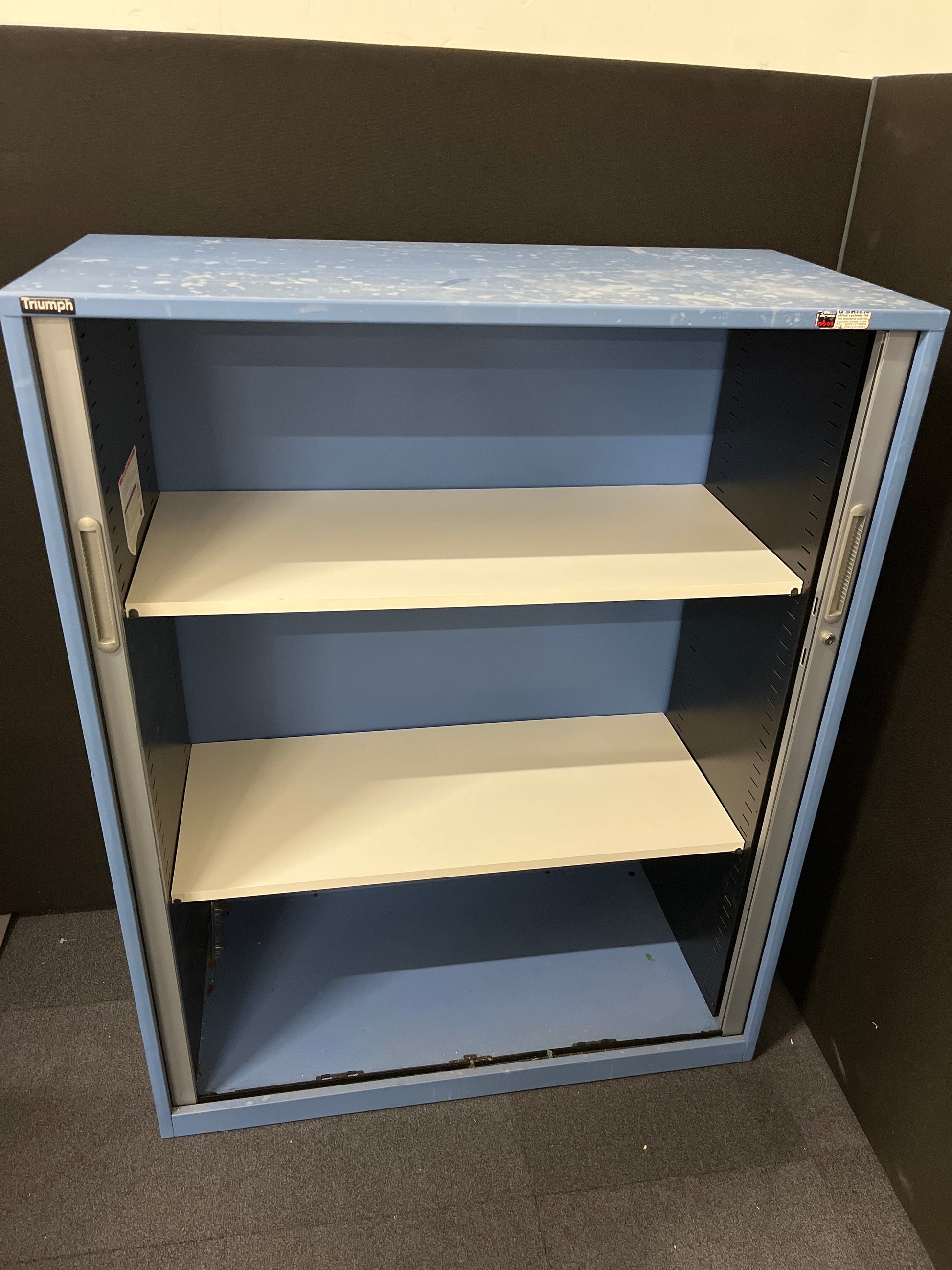 Secondhand Triumph Blue metal framed, silver plastic sliding door tambour  with 2 no. internal shelves and 1 no. key 1000Wx1290Hx475D