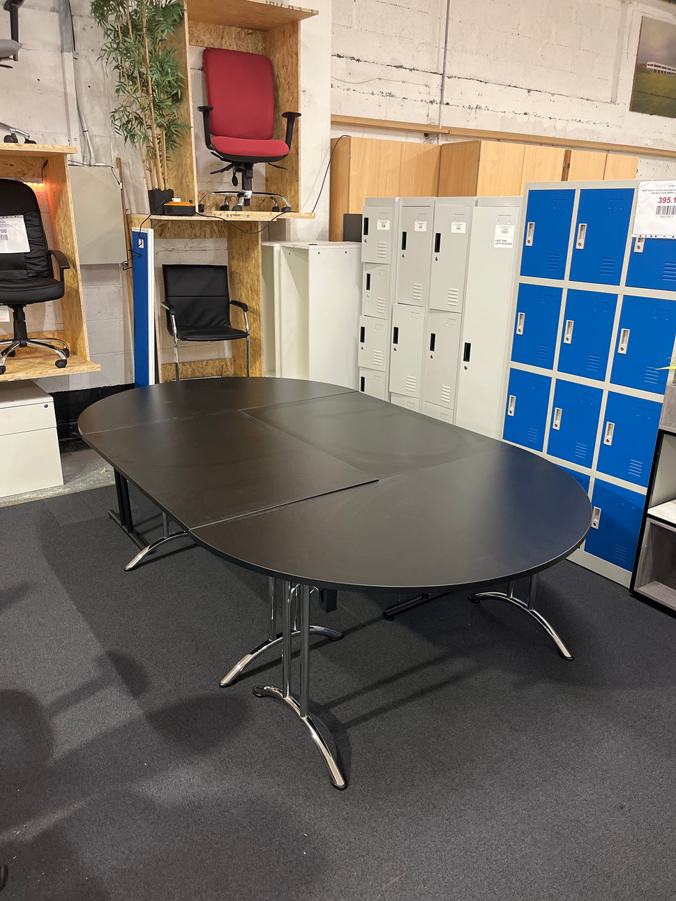 Large black oval shaped boardroom table  (length 2.8 m width 1.6 m) comprised of 2 black semi-circular foldable desks and 2 black straight foldable desks