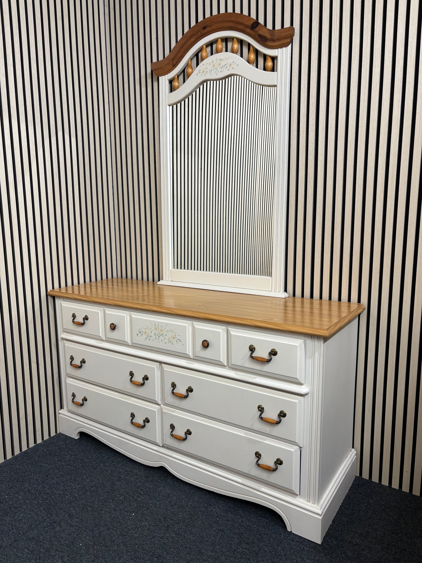 White dresser with a matching decorative mirror and floral accents