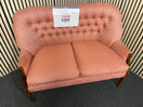 Two-seater sofa with pink geometric pattern and tufted backrest with slight wear to arm on LHS, solid wood frame. Ideal for