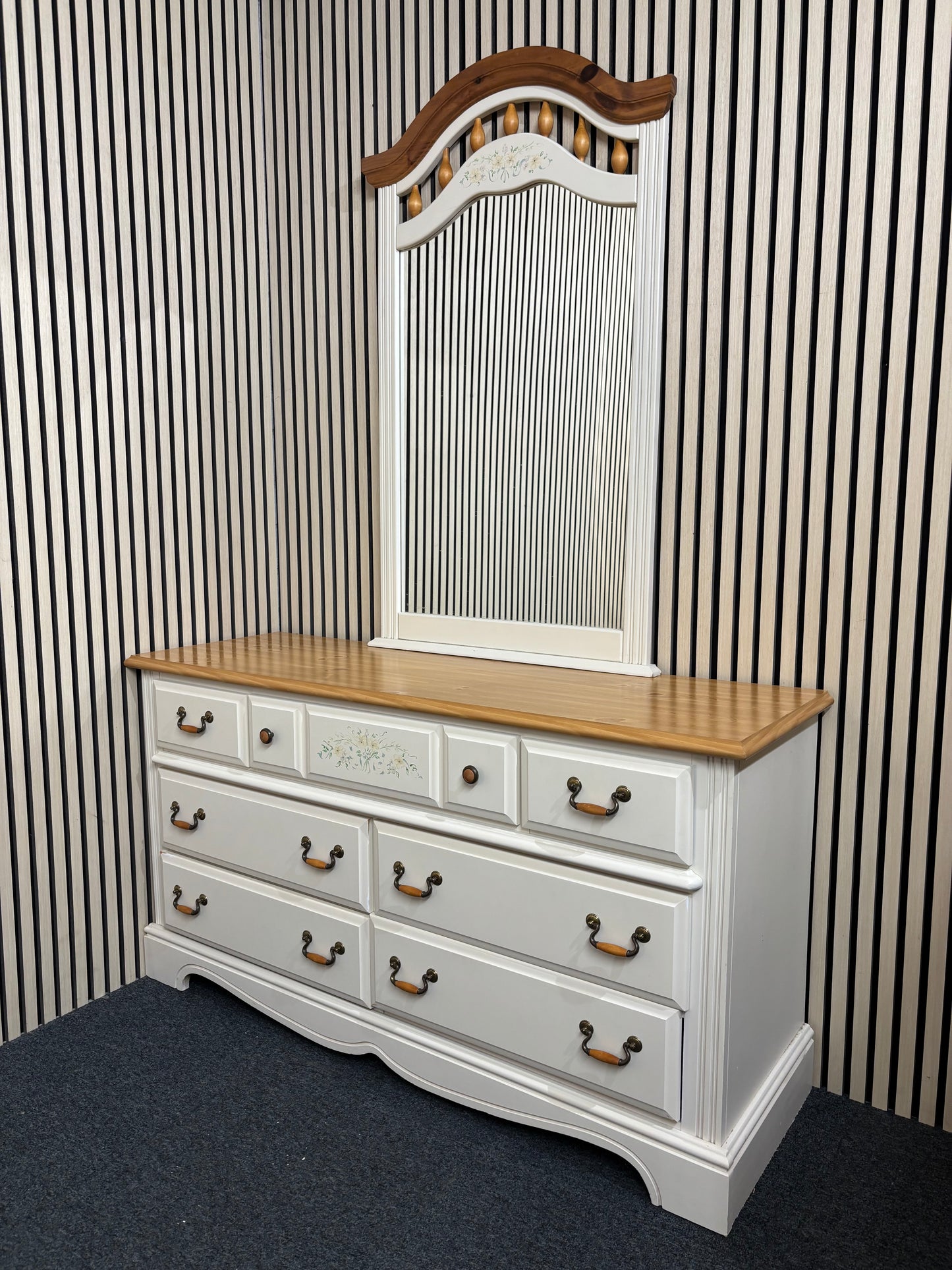 White dresser with a matching decorative mirror and floral accents