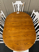 Oval wood dining table with six white spindle back chairs.  44515