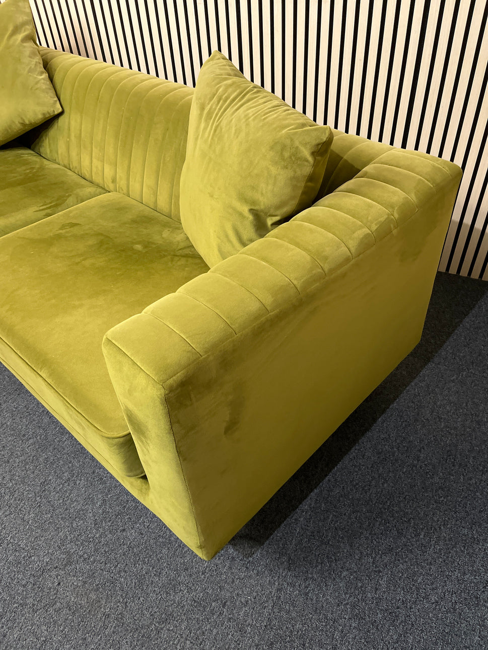 Modern olive green velvet sofa with vertical channel tufting, 2 seat cushions and slim black legs assencted with gold tips( W x 197 L x 81 H x 73 cm)