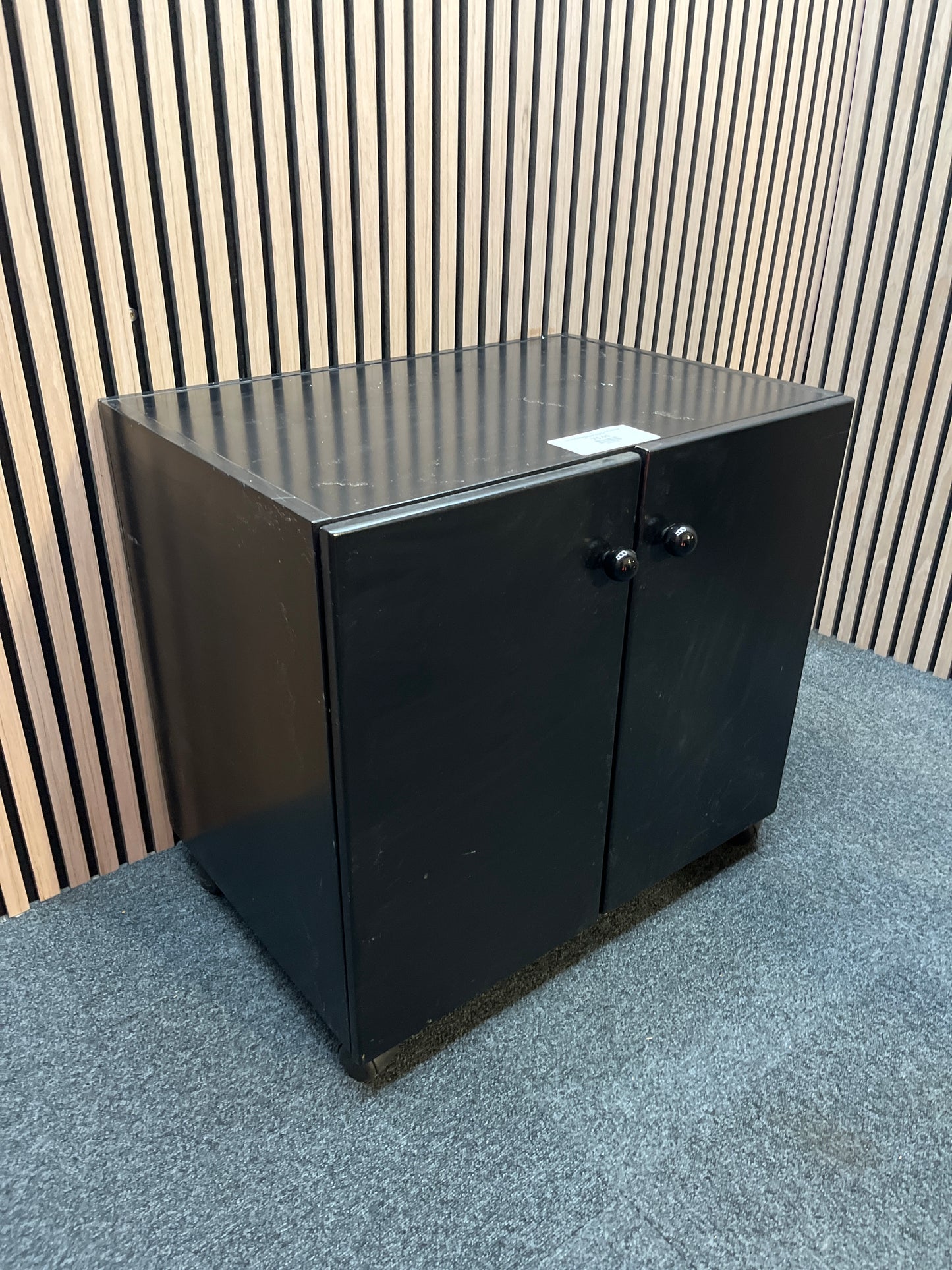 Low black laminate two door storage unit on castors (H 66 x W 70 x D 50 cm)