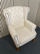 Beige tufted wingback armchair with decorative black nailhead trim detail.  44518