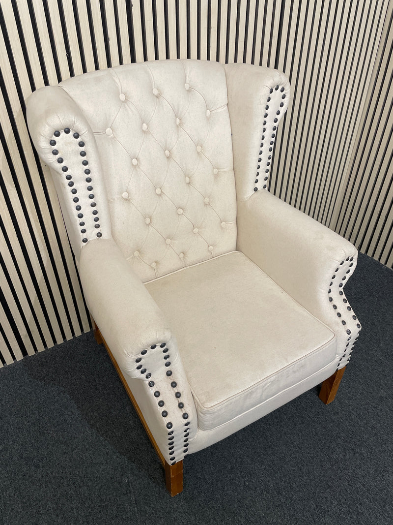 Beige tufted wingback armchair with decorative black nailhead trim detail.  44518