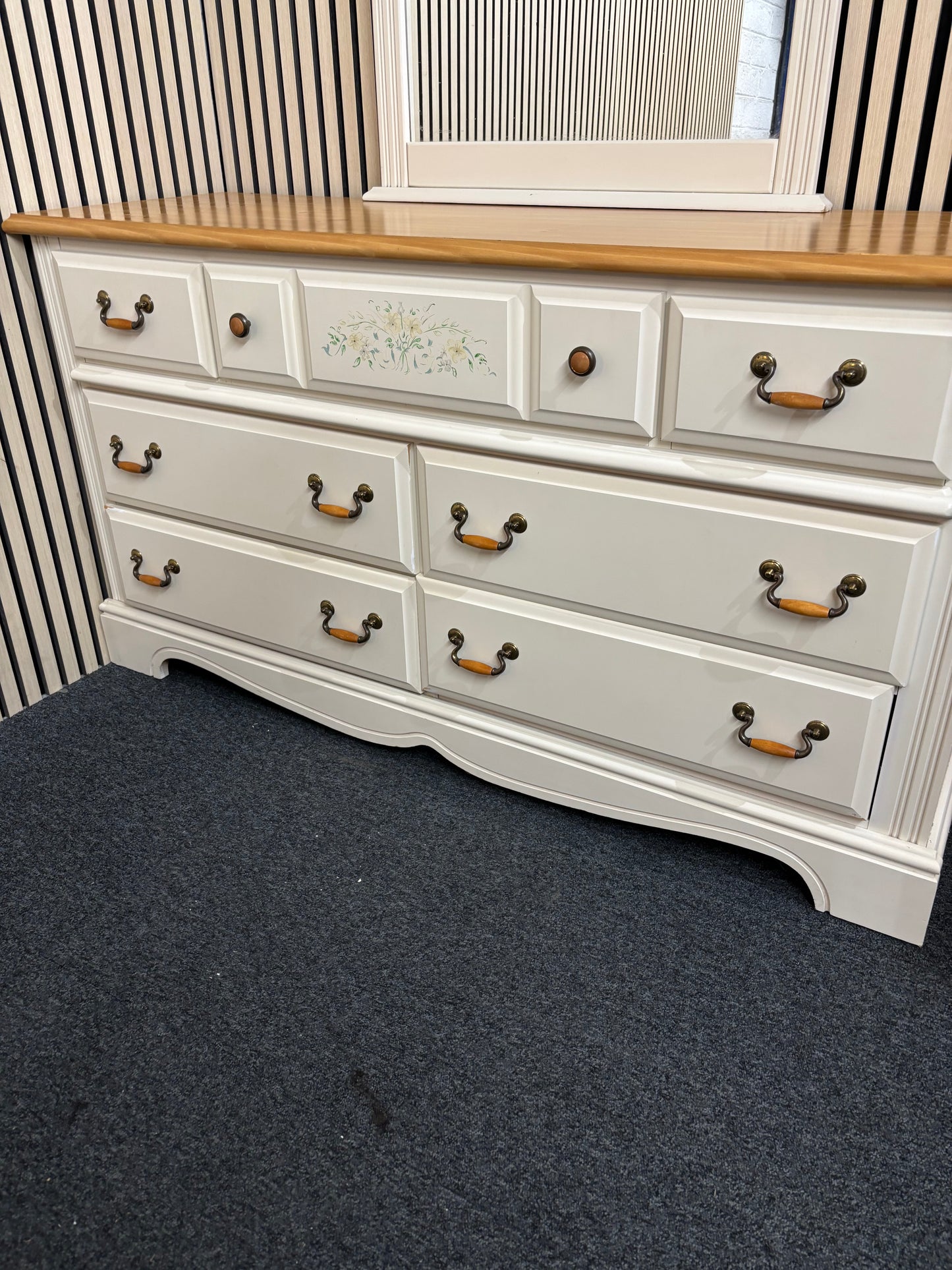 White dresser with a matching decorative mirror and floral accents