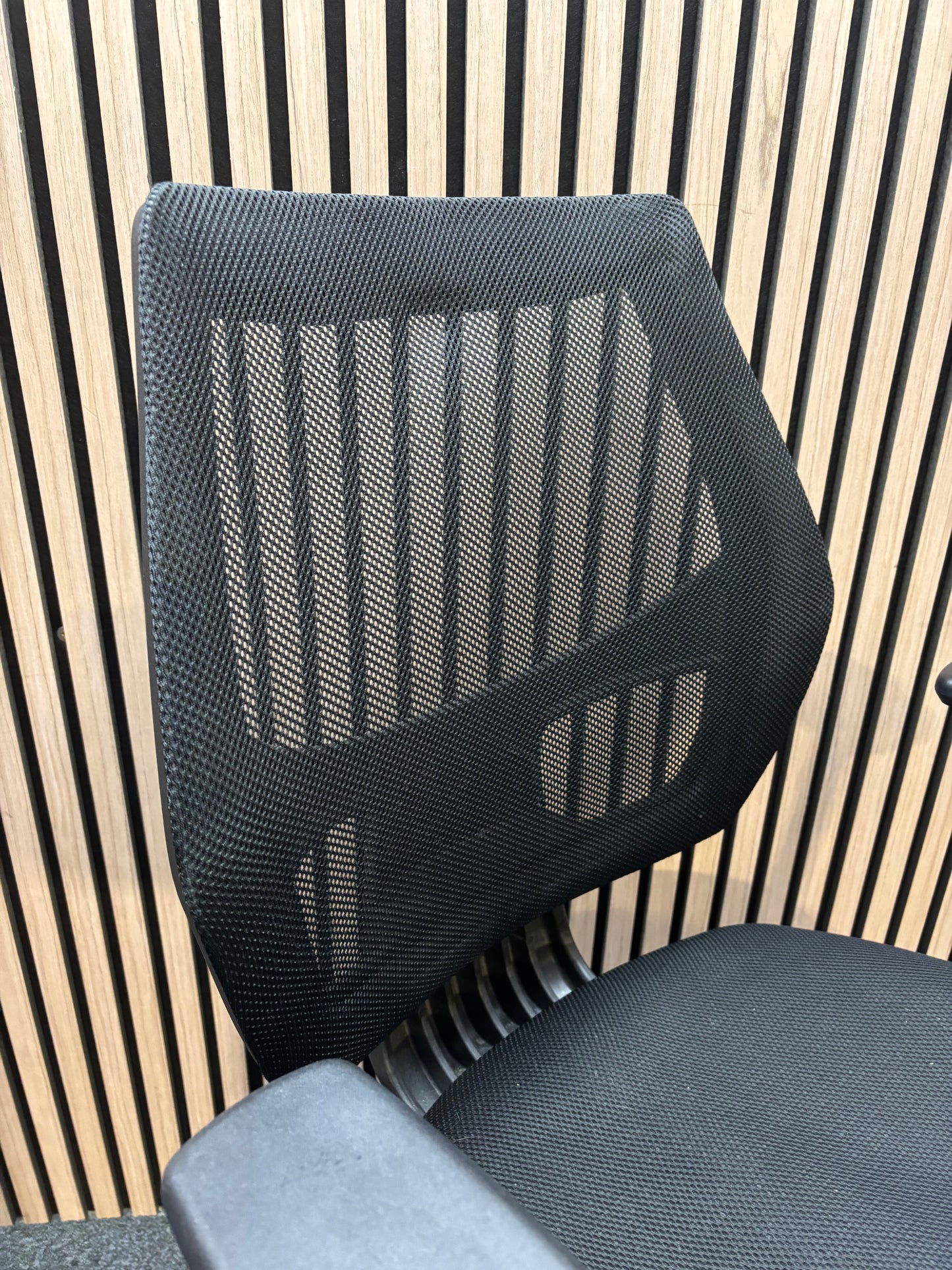 Black mesh back second hand swivel chair with adjustable arms and black fabric seat